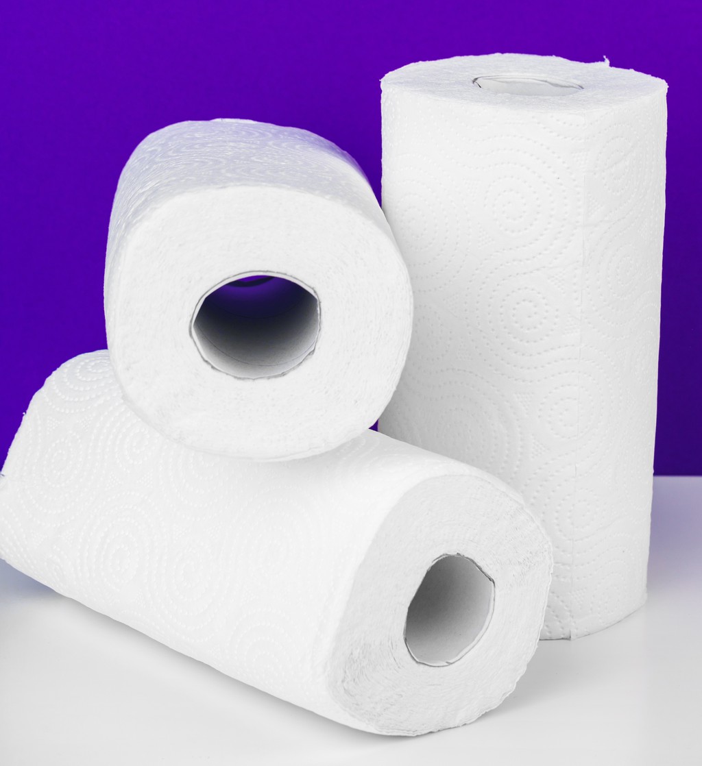 Roll of paper towel on table against purple background